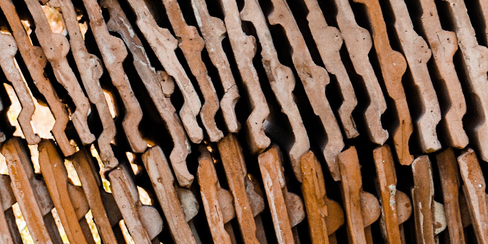 Close-up of an intricate pattern of interlocking, weathered orange and brown metal pieces creating a textured surface.