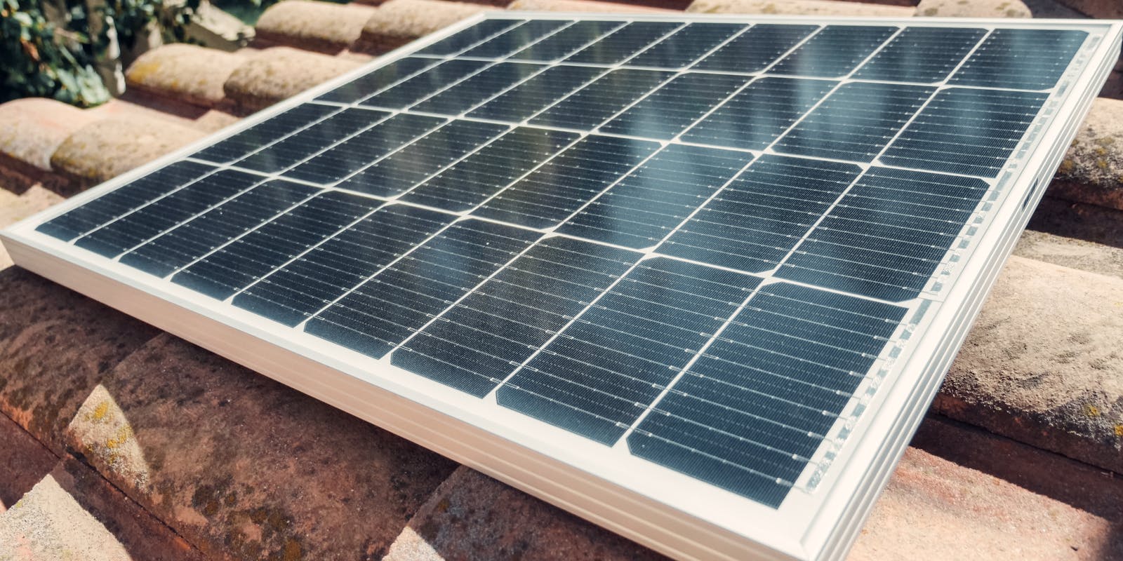 A solar panel installed on a tiled roof, under sunlight.