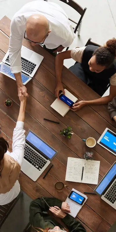 Équipe collaborant sur des tâches administratives en ligne avec des ordinateurs portables et des tablettes, illustrant l'efficacité des services d'assistanat virtuel pour entreprises."
