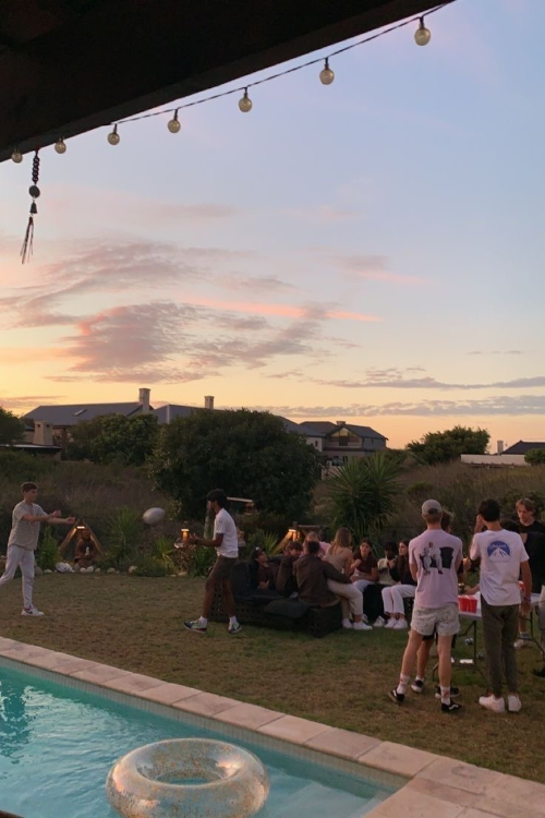 Groupe de jeunes autour d'une piscine au coucher de soleil, profitant d'une soirée en plein air avec ambiance détendue