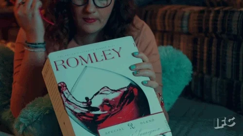 Femme portant des lunettes, qui sirote un cubi de rosé à la paille