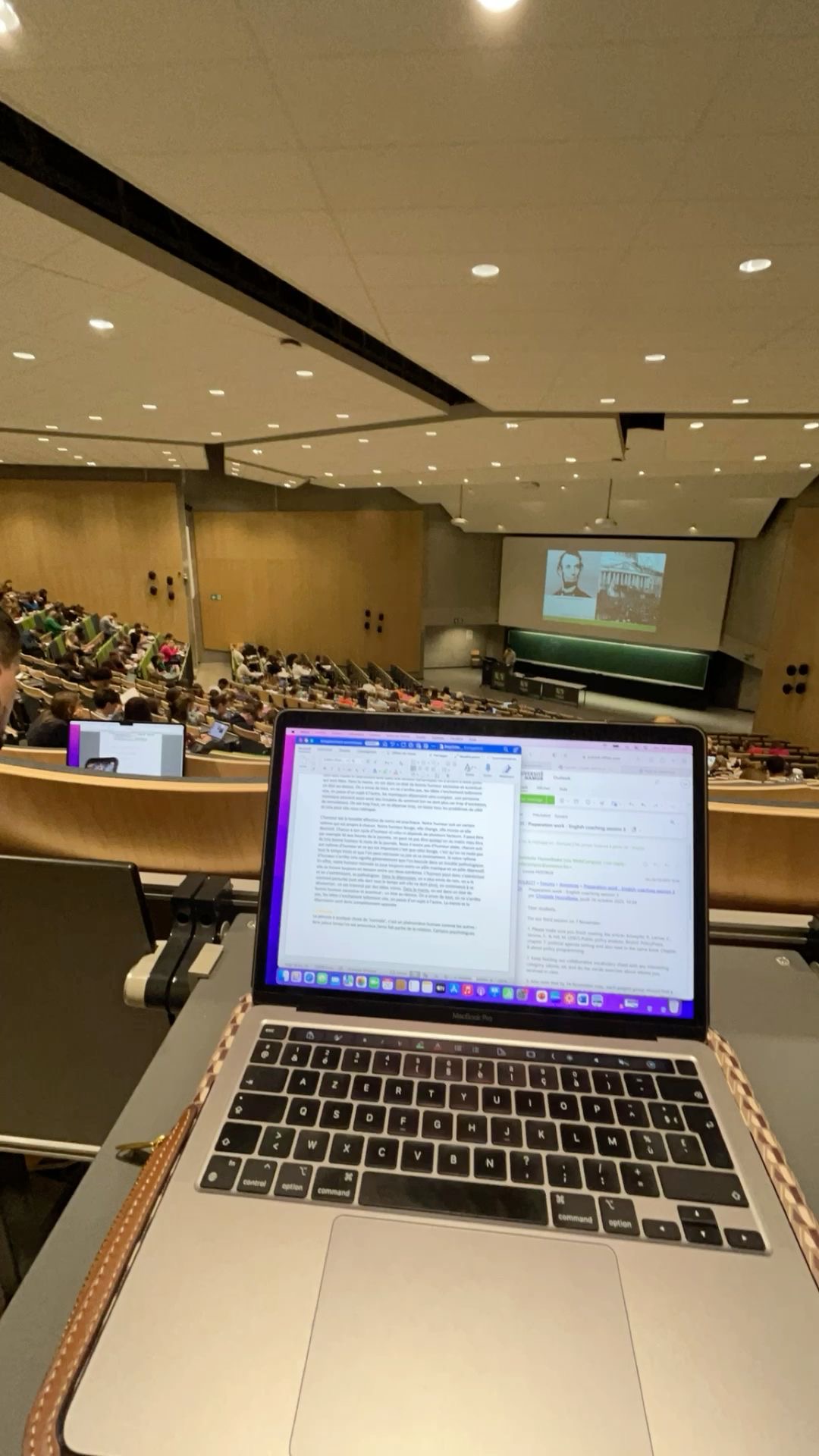 Amphithéâtre universitaire avec un ordinateur portable ouvert en premier plan, capturant un cours ou une conférence