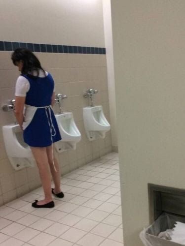 Personne en tenue bleue utilisant des urinoirs dans un cadre public, capturant une scène inhabituelle