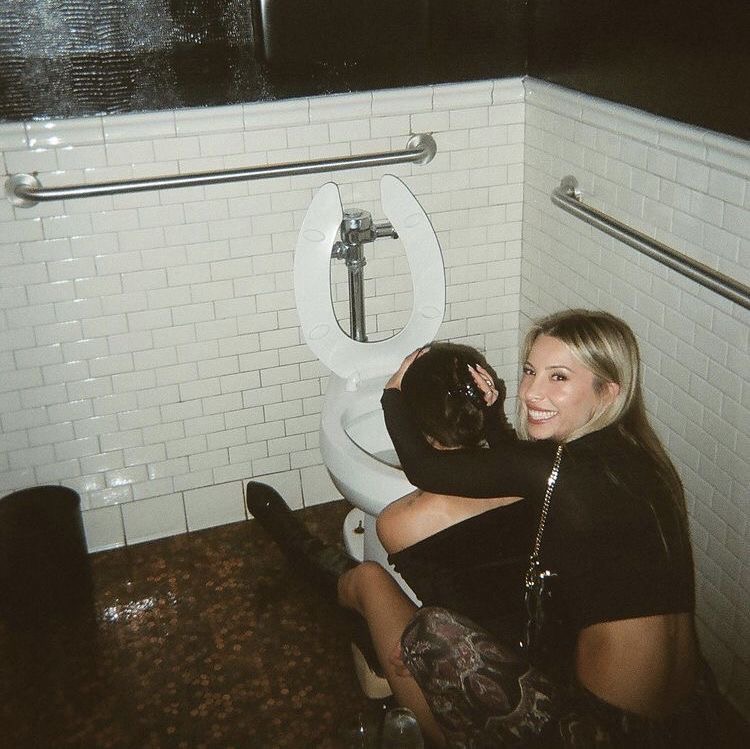 Personne réconfortant un ami près des toilettes dans un contexte de soirée, évoquant une scène typique après un excès festif.
