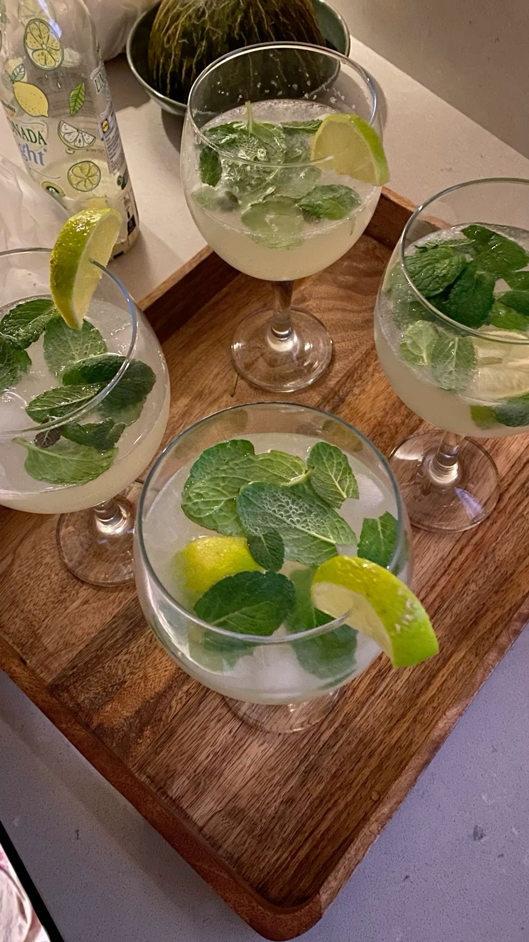 Plateau en bois avec plusieurs verres de mojito garnis de feuilles de menthe fraîche, de rondelles de citron vert et de glaçons