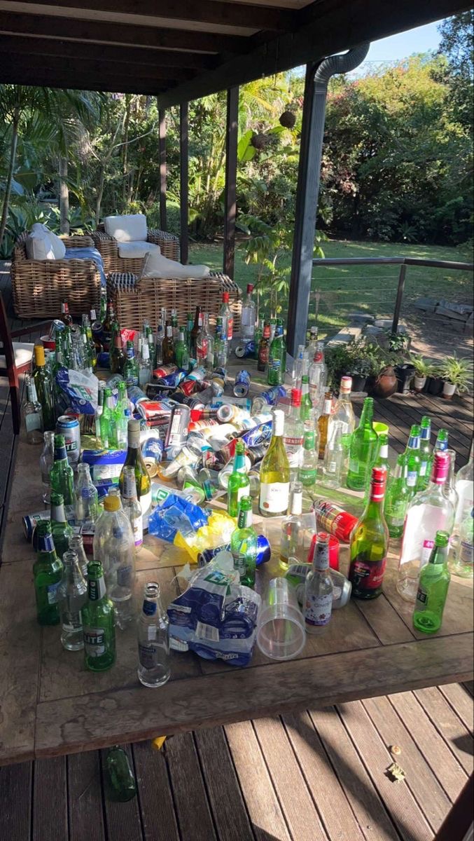 Table en extérieur jonchée de bouteilles vides et d'emballages, témoignant d'une soirée animée