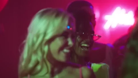 Deux personnes souriantes dans une ambiance festive avec des lumières colorées