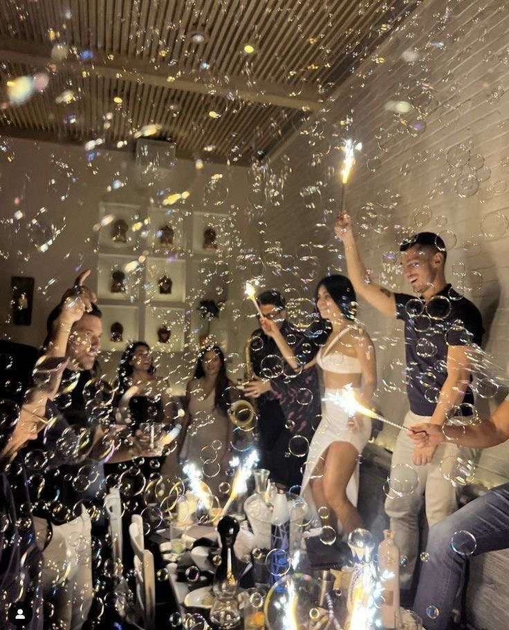 Ambiance festive avec des bulles, des étincelles et un groupe de personnes célébrant dans une soirée animée