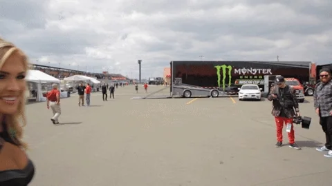 Femme souriante en extérieur, avec un camion Monster Energy en arrière-plan sur un parking