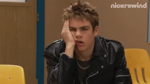 Jeune homme avec une expression ennuyée, appuyant sa tête sur sa main, portant une veste en cuir