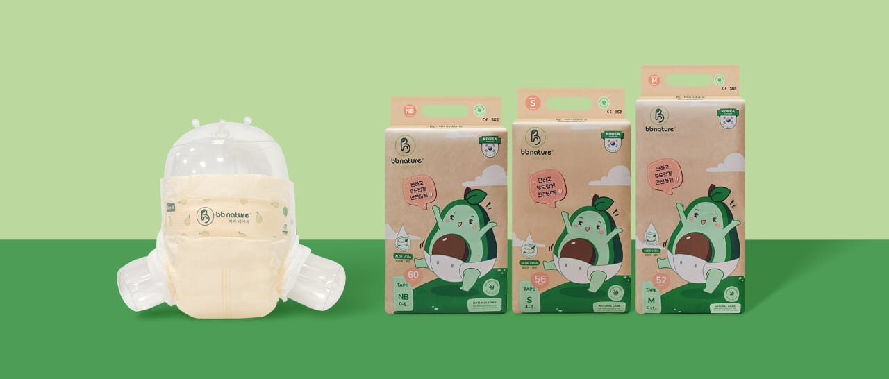 Wood table with porcelain mug, leather journal, brass pen, leather key ring, and a houseplant.